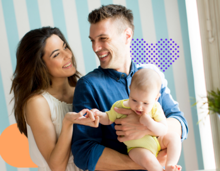 A woman smiling to a man who is holding a baby while smiling back at her. Family
