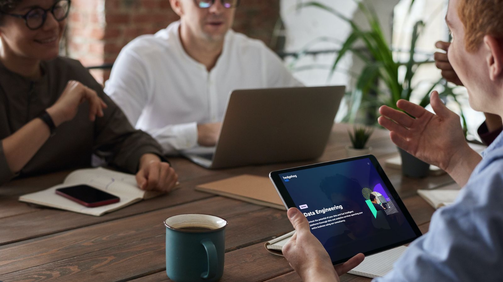 people talking in a meeting room with laptops in front of them