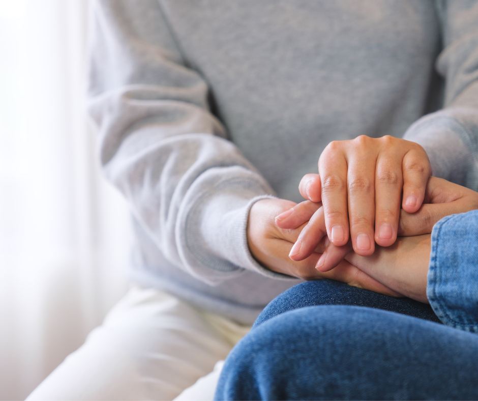 A person is being comforted by having their hands placed in between another person's hands. The image is used to reflect charities and social impact organisations.