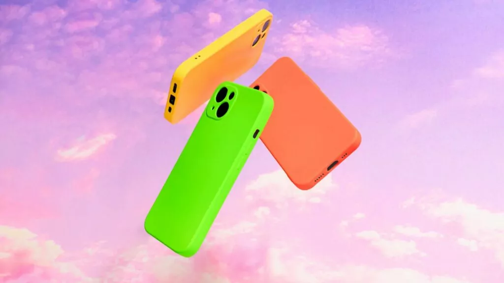 Three bright-coloured phones in yellow, orange and neon green floating in a circle against an abstract purple, cloudy sky.